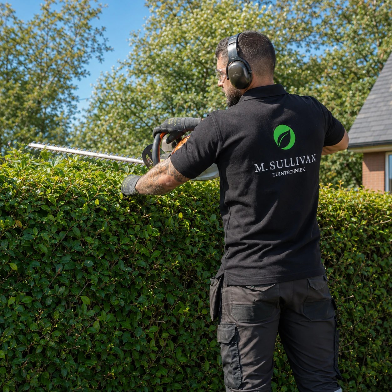 hovenier in groene werkpolo bij heg